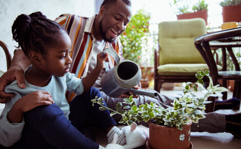 Dad and daughter watering house plant