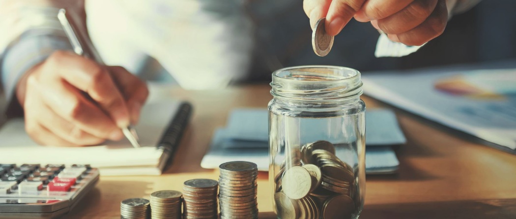 a person putting coins in a glass jar