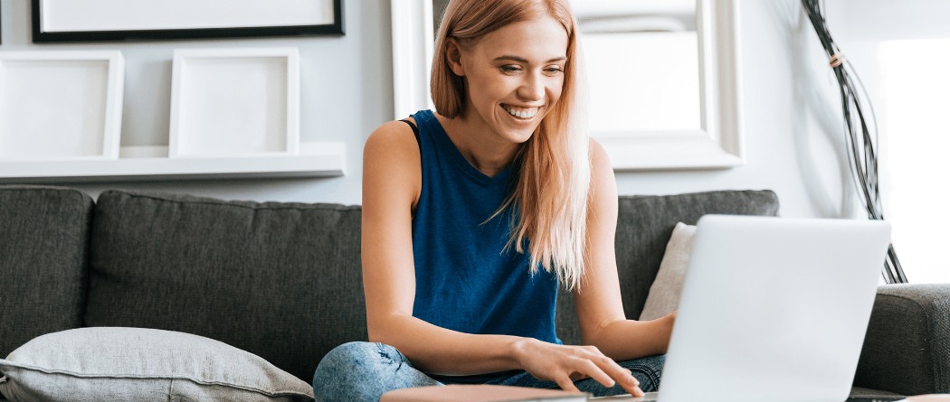 woman sitting on a couch looking at her laptop