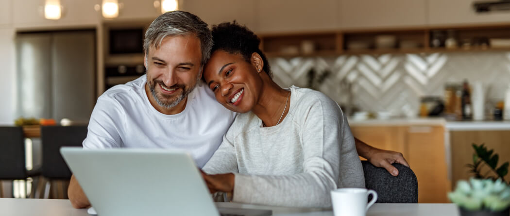 a couple in their kitchen looking at their laptop